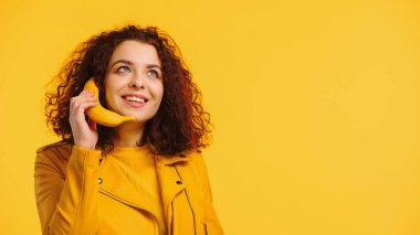 Mutlu kadın telefon konuşmasını taklit ediyor muz sarıda izole edilmiş.