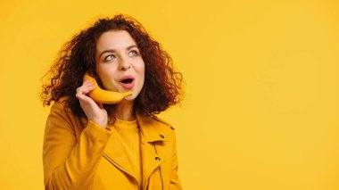 Sarı üzerine izole edilmiş muz ile telefon konuşmasını taklit eden pozitif kadın