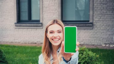 Binaya yakın yeşil ekranlı akıllı telefon tutan neşeli öğrenci. 