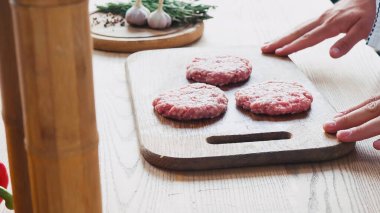 cropped view of chef near formed mince patty on chopping board  clipart