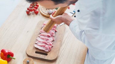 partial view of chef with salt mill seasoning sliced beef tenderloin  clipart