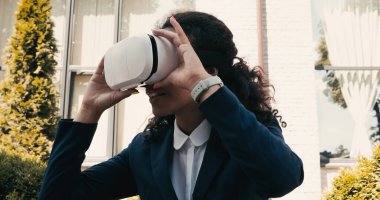 Memnun Afro-Amerikan iş kadını dışarıda VR kulaklık kullanıyor.