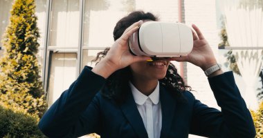 Neşeli Afro-Amerikan iş kadını dışarıda VR kulaklık kullanıyor.