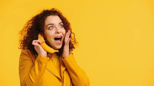 Erstaunte Frau Imitiert Telefongespräch Mit Banane Isoliert Auf Gelb — Stockfoto