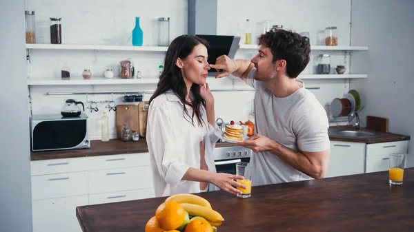 Young Man Touching Nose Girlfriend Unbuttoned Shirt While Holding Pancakes — Stock Photo, Image