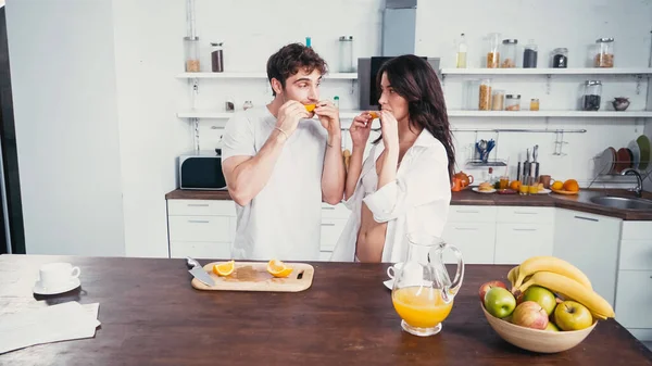 Young Man Sexy Woman Bra Shirt Eating Ripe Orange Kitchen — Stock Photo, Image