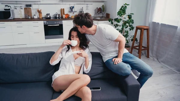 남자가 셔츠와 브라를 커피를 마시는 여자의 머리에 키스하는 — 스톡 사진