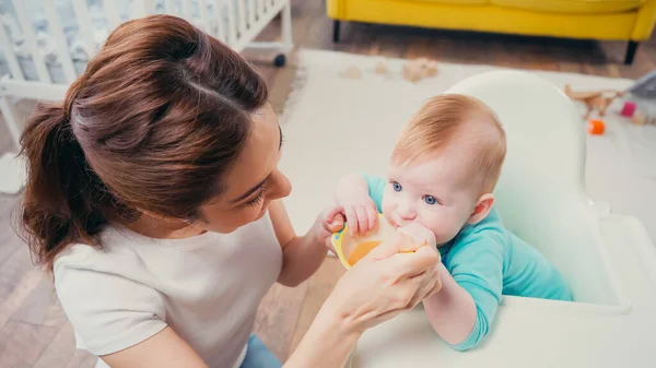 高い角度ビューのブルネットの母親は赤ちゃんの食べ物で幼児の息子を食べ — ストック写真