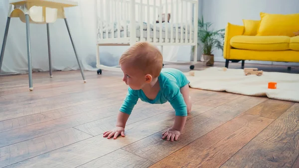男婴爬到客厅里靠近喂食椅的地板上 — 图库照片