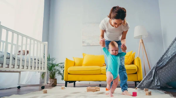 Mãe Feliz Mãos Dadas Apoiando Filho Infantil Andando Sobre Cobertor — Fotografia de Stock