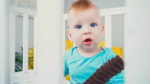 Surprised Baby Boy Sitting Blurred Baby Crib Soft Toy — Stock Photo, Image