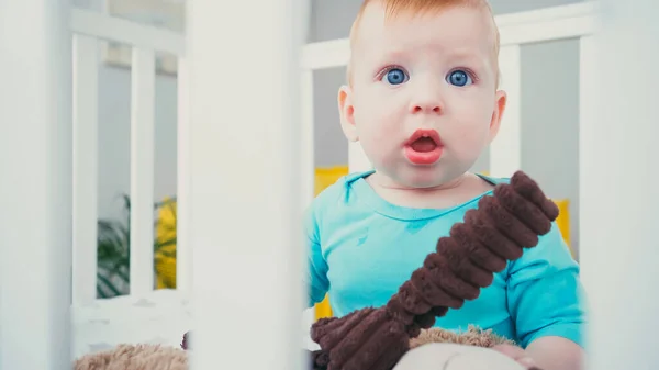 Menino Infantil Surpreso Sentado Berço Bebê Borrado Com Brinquedo Macio — Fotografia de Stock