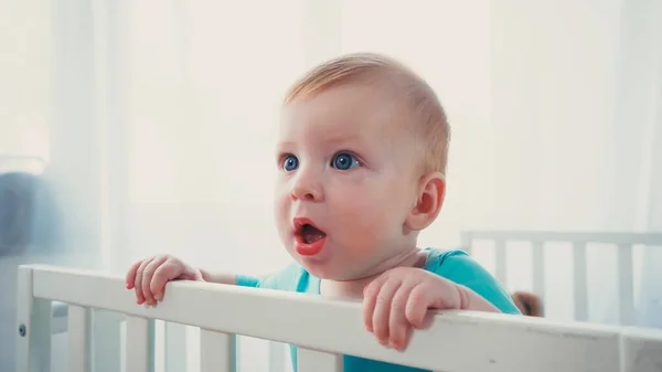 赤ちゃんのベビーベッドに立って目を背けて — ストック写真
