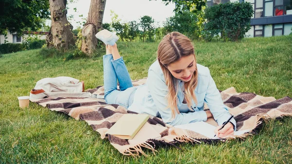 Estudiante Alegre Escritura Cuaderno Cerca Libros Mientras Que Miente Manta —  Fotos de Stock