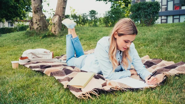 Estudiante Escribiendo Cuaderno Cerca Libros Mientras Está Acostado Manta Parque —  Fotos de Stock