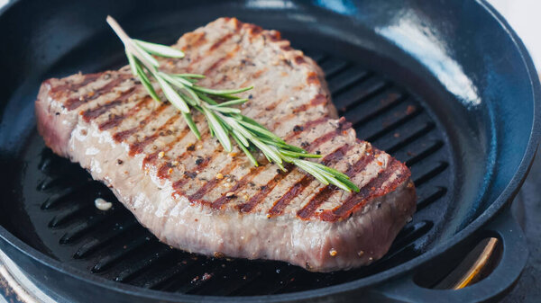 close up of fresh rosemary branch on fried beef steak 