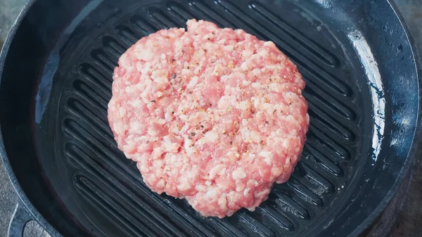 close up of mince patty with black pepper on hot pan