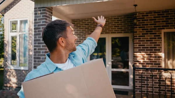 Hombre Feliz Sosteniendo Caja Señalando Con Mano Casa — Foto de Stock