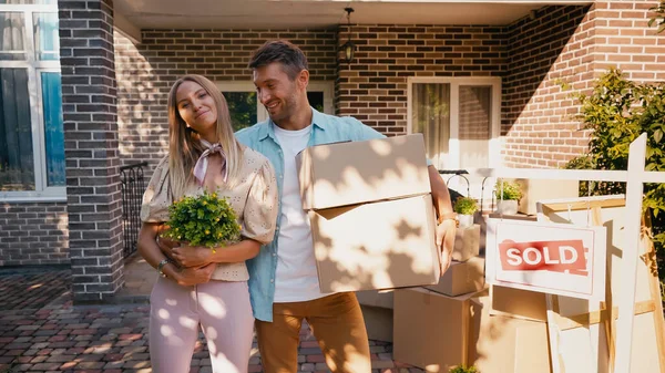 Homme Joyeux Étreignant Femme Avec Plante Debout Près Nouvelle Maison — Photo