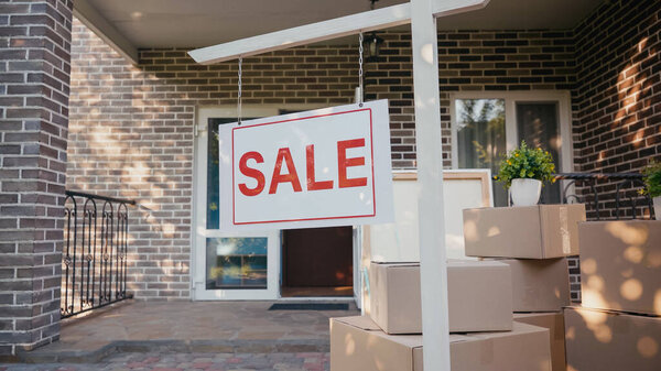 sticky label with sale lettering on board near new modern house