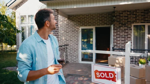 Hombre Alegre Sosteniendo Copa Vino Tinto Mirando Nueva Casa — Foto de Stock