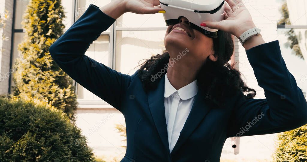 Happy african american businesswoman using vr headset outside