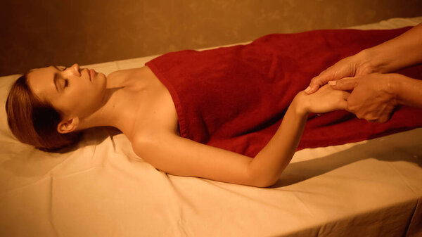 pretty client with closed eyes receiving hand massage from masseur in spa salon