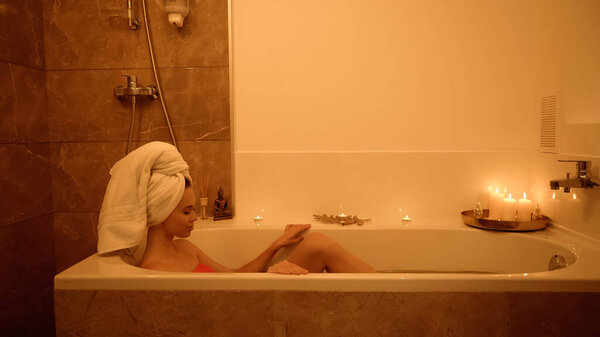 side view of pleased woman in bathtub with water in wellness center