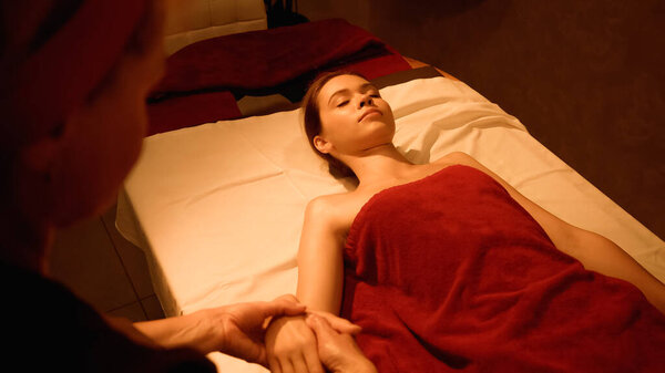 woman with closed eyes receiving hand massage from blurred professional masseur