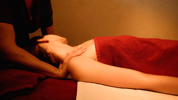 woman receiving neck massage from professional masseur in spa salon