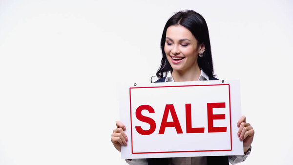 Smiling broker looking at signboard with sale lettering isolated on white