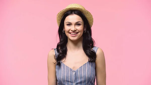 Güneş şapkalı olumlu kadın pembe kameraya bakıyor. 