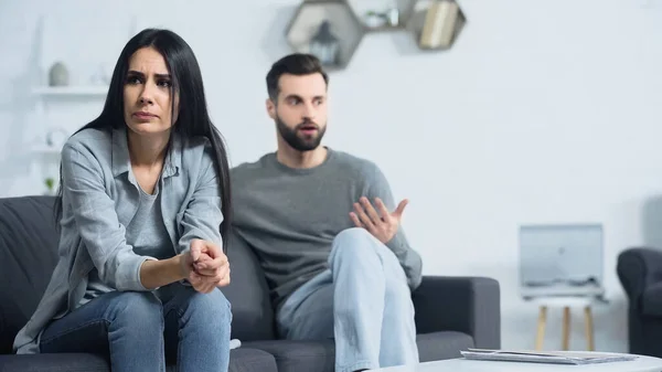 Worried Woman Sitting Clenched Hands Blurred Displeased Boyfriend — 스톡 사진