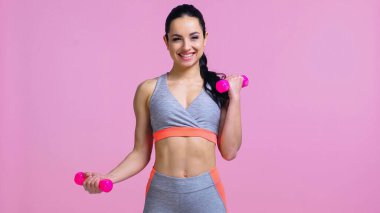 Pembeye izole edilmiş halterlerle spor yapan neşeli sporcu kadın. 