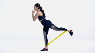 Beyaz üzerinde elastiklerle egzersiz yapan genç sporcunun yan görünüşü