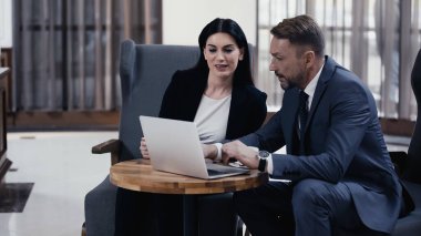 Business partners using laptop in restaurant lobby
