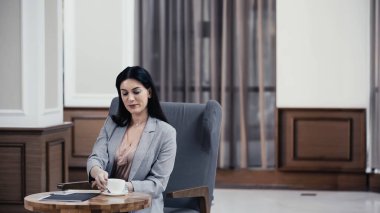 Businesswoman reaching cup of coffee in restaurant