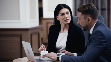 businesswoman looking at man using laptop in restaurant 