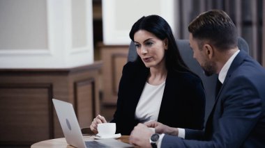businessman looking at woman using laptop in restaurant 