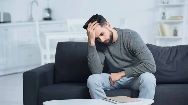 stressed man looking at folder and touching head at home