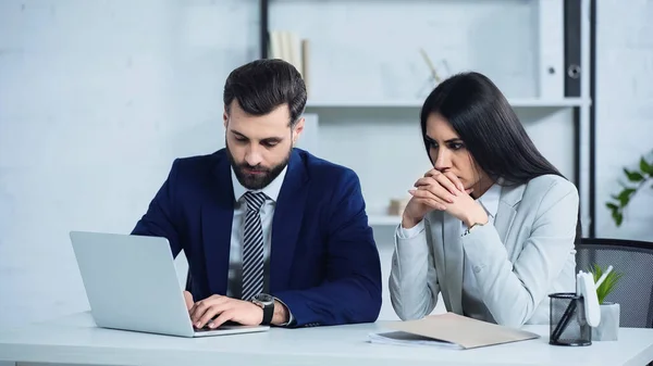 Zmartwiony Businesswoman Zaciśniętymi Rękami Siedzi Pobliżu Menedżera Pomocą Laptopa Biurze — Zdjęcie stockowe