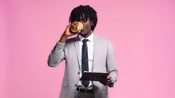 Afrikanischer Geschäftsmann Schaut Auf Klemmbrett Während Kaffee Isoliert Auf Rosa — Stockfoto
