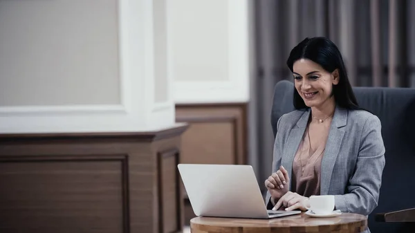 Happy Businesswoman Having Video Call Laptop Cup Coffee Table Lobby — Zdjęcie stockowe