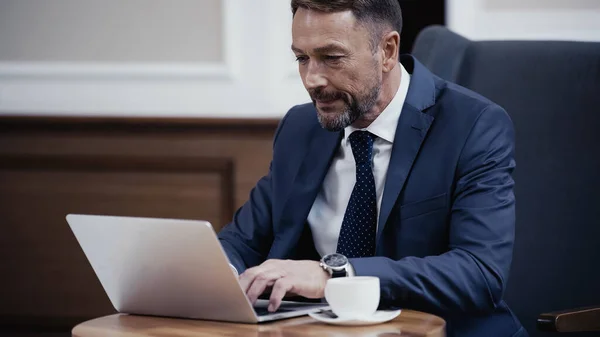 Geschäftsmann Benutzt Laptop Der Nähe Einer Tasse Kaffee Der Lobby — Stockfoto