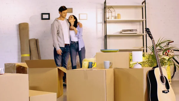 Blurred Man Hugging Pleased Girlfriend Carton Boxes New Home — Stock Photo, Image