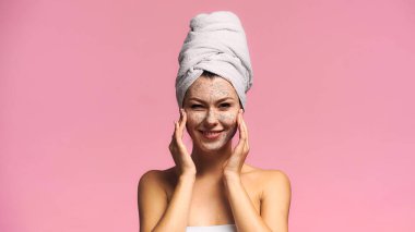 Neşeli kadın temizlik maskesi takıyor ve pembe kameraya bakıyor.