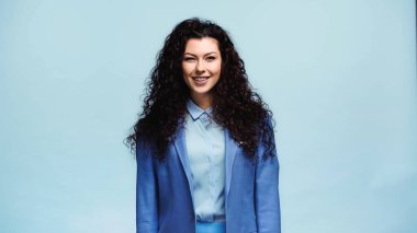 Neşeli esmer kadın mavi kameraya bakıyor.