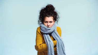 Sıcak süveter ve eşarplı kadın soğuktan donarken kendine sarılıyor.