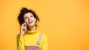 Mutlu ve hayalperest kadın portakalda izole bir şekilde cep telefonundan ararken yüzünü çeviriyor.
