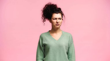 displeased woman in green pullover looking away isolated on pink clipart